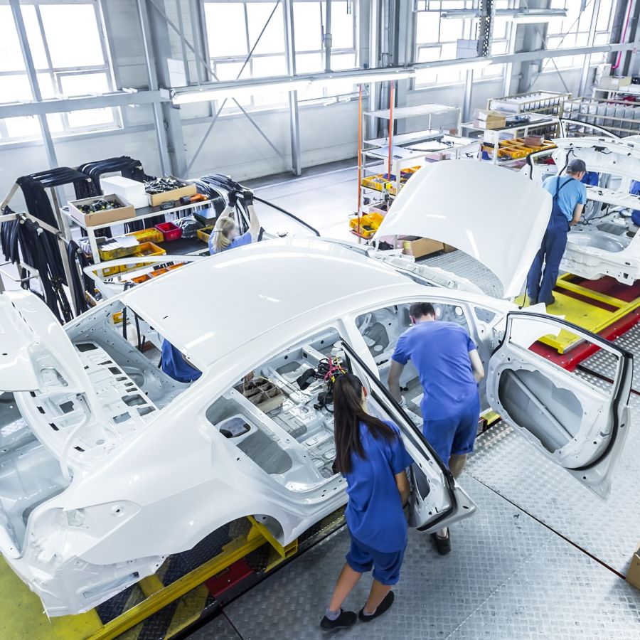 zeigt Mitarbeitende in der Fertigung von Autos
